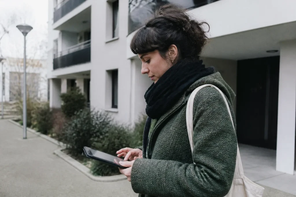 Agent recenseur tenant une tablette devant un immeuble collectif