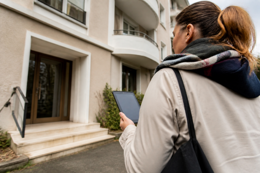 Agent recenseur tenant une tablette devant un immeuble