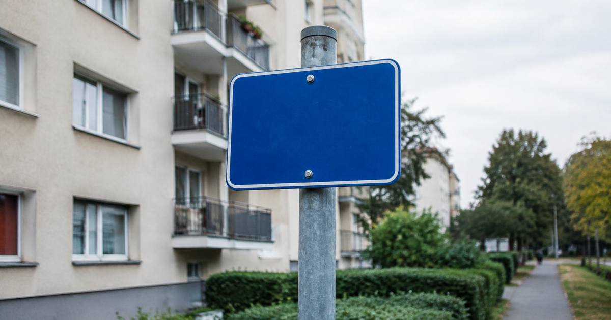 Pancarte bleue fixee sur poteau devant des immeubles residentiels